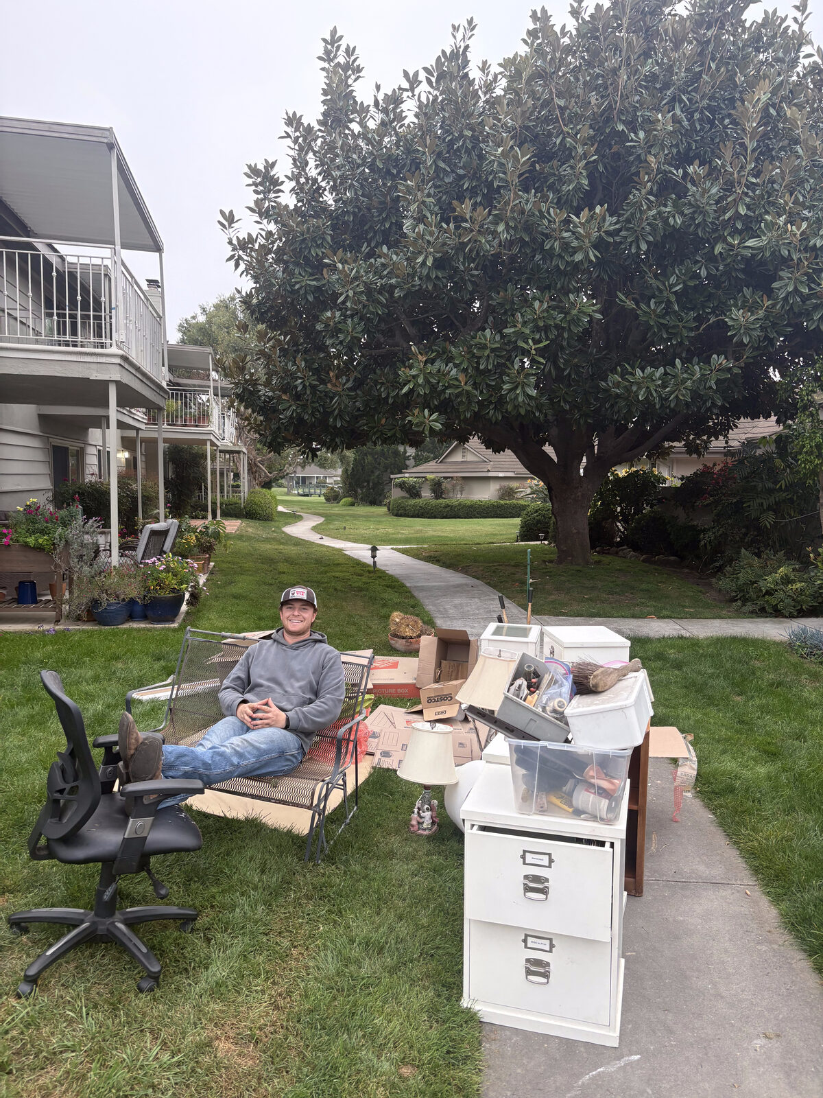 Jack taking a break next to furniture and office equipment staged for pickup during a residential junk removal job in Santa Barbara County