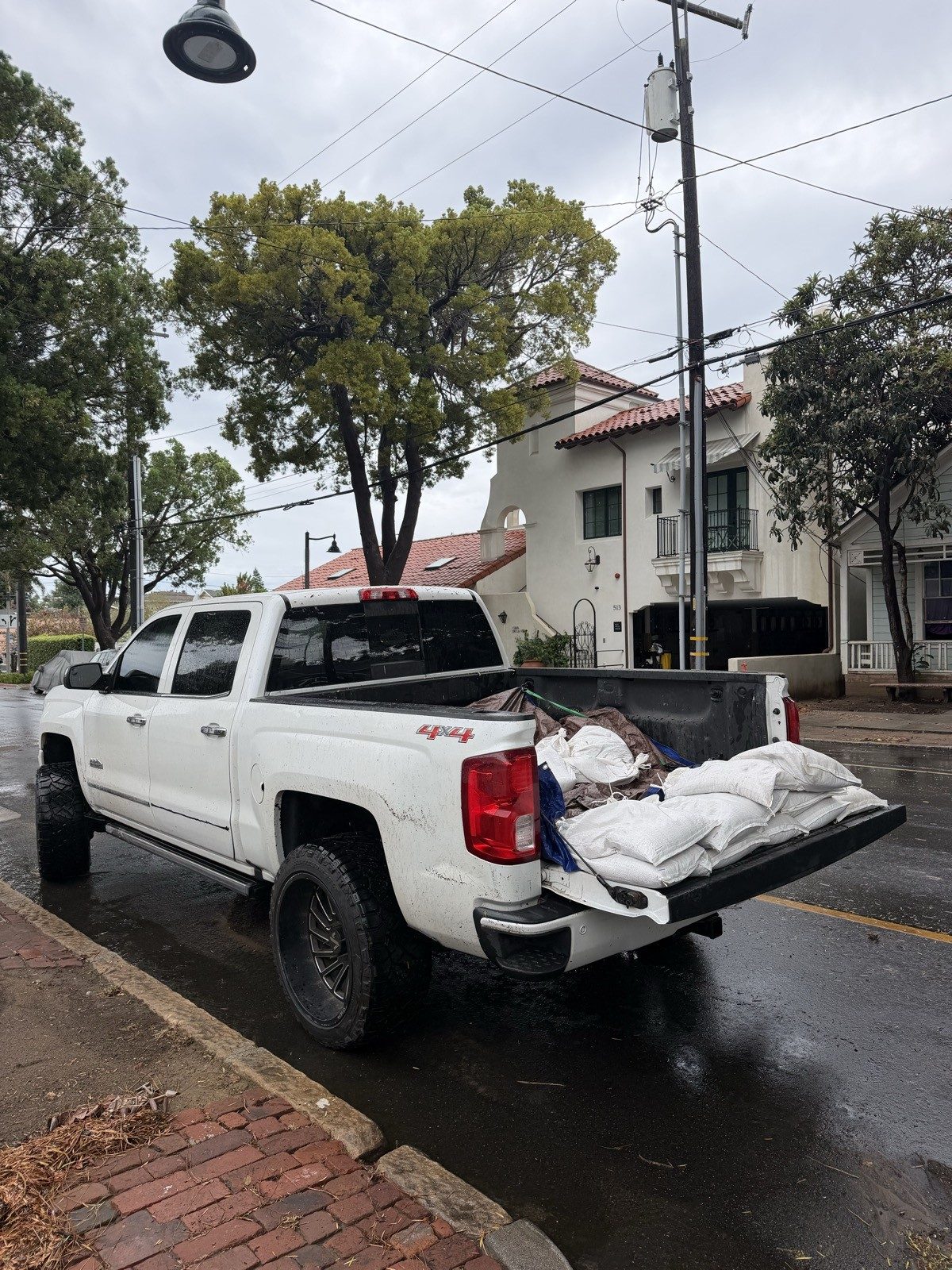 Jack's Junk Removal truck loaded with filled sandbags on a rainy Santa Barbara street